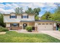 Charming two-story home with a well-manicured front yard, brick accents, and an attached two-car garage at 6251 W 74Th Ave, Arvada, CO 80003