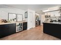 Charming kitchen boasts brick accent wall, modern appliances, wine storage, and sleek black and white cabinets at 6251 W 74Th Ave, Arvada, CO 80003