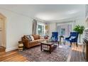 Inviting living room features hardwood floors, a comfortable leather sofa, blue accent chairs, and a stylish rug at 1235 Dahlia St, Denver, CO 80220