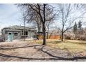 Large backyard with mature trees, gravel parking, and covered outdoor seating area at 2030 Cody St, Lakewood, CO 80215