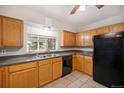 Kitchen featuring wood cabinets, black appliances, and double sink under a large window at 1445 S Eaton St, Lakewood, CO 80232