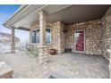 Charming covered front porch featuring stone columns and a cozy seating area at 7603 Yule Ct, Arvada, CO 80007