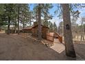Rustic log cabin featuring a wooden walkway and deck surrounded by tall trees on a hillside at 27888 Richmond Hill Rd, Conifer, CO 80433