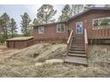 Exterior of a cozy home with wood siding and a detached garage nestled in a wooded area, offering privacy at 31168 Witteman Rd, Conifer, CO 80433