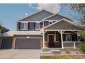 Charming two-story home with a three car garage, covered porch, gray siding and brick accents at 3725 S Nepal St, Aurora, CO 80013