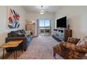 Comfortable living room with couch, TV, patterned chair, and sliding glass door to balcony at 9962 W Victoria Pl # 106, Littleton, CO 80127