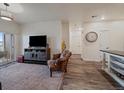 Cozy living room with wood floors, a large rug, a tv, and an armchair in front of a sliding glass door at 9962 W Victoria Pl # 106, Littleton, CO 80127