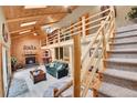 Beautiful living room boasting vaulted ceilings, a fireplace, log railing, and staircase leading to the upper level at 11182 S Barney Gulch Rd, Conifer, CO 80433
