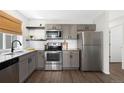 Modern kitchen features stainless steel appliances, sleek gray cabinets, and granite countertops offering style at 17767 E 54Th Ave, Denver, CO 80249