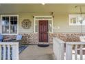 Inviting front porch featuring stone accents, a dark wooden door, and space for seating at 3406 Purcell St, Brighton, CO 80601