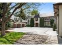 Elegant home featuring a circular driveway, three-car garage, and mature trees at 5 Churchill Dr, Cherry Hills Village, CO 80113