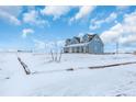 Blue two-story house with a large yard, covered porch, and snowy landscape at 14199 County Road 26, Fort Lupton, CO 80621