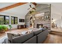 Inviting living room with a stone fireplace, wood floors, a vaulted ceiling, and natural light filtering through the windows at 28833 Western Dr, Evergreen, CO 80439