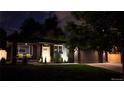 Charming single-story home featuring a sleek dark gray exterior, lush green lawn, and a modern garage door at night at 1830 S Fillmore St, Denver, CO 80210