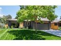 Charming single-story home featuring a sleek dark gray exterior, lush green lawn, and a modern garage door at 1830 S Fillmore St, Denver, CO 80210
