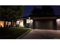 Charming single-story home featuring a sleek dark gray exterior, lush green lawn, and a modern garage door at night at 1830 S Fillmore St, Denver, CO 80210