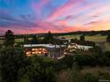 Sweeping aerial view of large, well-kept property with surrounding trees and landscaping at dusk at 3675 S Perry Park Rd, Sedalia, CO 80135