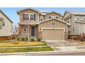 Two-story home with a two-car garage, stone accents, blue shutters, and a well-manicured front yard at 17859 E 108Th Pl, Commerce City, CO 80022