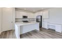 Well-lit kitchen with white cabinets, a kitchen island, stainless steel appliances, and hardwood floors at 15153 W Dequesne Ave, Morrison, CO 80465