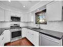 Modern kitchen featuring white cabinets, stainless steel appliances, black countertops, and subway tile backsplash at 1342 S Andes St, Aurora, CO 80017