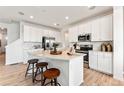 Modern kitchen featuring white cabinetry, stainless steel appliances, and an island with seating, perfect for entertaining and cooking at 3373 N Catawba Way, Aurora, CO 80019