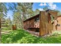 Exterior shot of a wood home with a grassy yard and mature trees at 4407 Delaware Dr, Larkspur, CO 80118