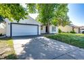 Exterior view of a home with a two-car garage and a large driveway, surrounded by lush greenery at 978 S Salida St, Aurora, CO 80017