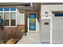 Inviting front porch with a blue door, decorative wreath, and neatly kept landscaping at 775 Woodgate Dr, Highlands Ranch, CO 80126