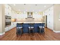 Bright kitchen with an island, white cabinets, a stainless steel refrigerator, and hardwood flooring at 775 Woodgate Dr, Highlands Ranch, CO 80126