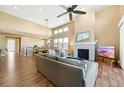 A spacious living room with hardwood flooring, fireplace, large windows, and a ceiling fan at 775 Woodgate Dr, Highlands Ranch, CO 80126