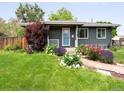 Charming gray home featuring manicured lawn, colorful flowerbeds and brick pathway at 6223 Gray St, Arvada, CO 80003