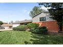 Well-manicured lawn and shrubbery surrounding an attractive home with brick and siding accents at 3322 Simms St, Wheat Ridge, CO 80033