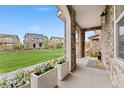 Inviting covered porch with stone columns, flower planters, and a welcoming entrance mat at 7602 S Yakima Ct, Aurora, CO 80016