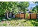 Landscaped front yard featuring a gray stone facade, mature trees, modern wood fence, and well-maintained lawn at 4570 Irving St, Denver, CO 80211