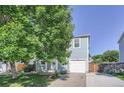 Charming two-story home featuring blue siding, a one car garage and mature trees at 1272 Bluebird St, Brighton, CO 80601