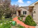 Charming front entrance with a colorful walkway, blooming tree, and lush landscaping enhancing curb appeal at 1590 Longview Cir, Monument, CO 80132