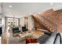 A spacious living room featuring exposed brick wall, modern staircase, hardwood floors and stylish furnishings at 3126 Perry St, Denver, CO 80212