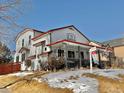 Two-story home with a wraparound porch and snowy yard at 395 Longspur Dr, Brighton, CO 80601