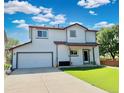 This two-story home includes an attached two-car garage and a well-kept lawn at 395 Longspur Dr, Brighton, CO 80601