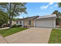 View of home with solar panels above garage, front yard and sidewalk leading to front door at 4425 S Zang St, Morrison, CO 80465
