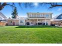 Expansive backyard featuring a covered patio, mature trees, and brick accents on a two-story home at 5775 S Pagosa Way, Centennial, CO 80015
