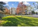 Scenic exterior view of a condominium complex with mature trees, green lawn, and a park bench at 13631 E Marina Dr # 201, Aurora, CO 80014