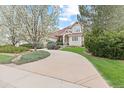Picturesque front exterior showcasing a circular driveway, mature trees, and beautifully landscaped yard at 16 Blue Heron Dr, Thornton, CO 80241