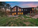 The backyard has a stone patio, large windows, and stairs leading up to a wooden balcony and fenced yard at 26452 Wolverine Trl, Evergreen, CO 80439