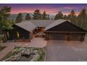 Home featuring a three-car garage, mountain views, inviting curb appeal, and rock garden with pond at 26452 Wolverine Trl, Evergreen, CO 80439