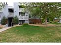 View of the exterior of the building on a grassy lawn with mature landscaping at 7665 E Eastman Ave # 111A, Denver, CO 80231