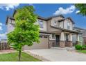 Charming two-story home featuring a manicured lawn and a welcoming front porch with stone accents at 676 Fossil Bed Cir, Erie, CO 80516