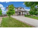 Charming two-story home featuring a manicured lawn and a welcoming front porch with stone accents at 676 Fossil Bed Cir, Erie, CO 80516