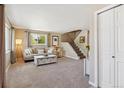 Cozy living room featuring neutral tones, plush carpeting, and staircase access at 11402 W 17Th Pl, Lakewood, CO 80215