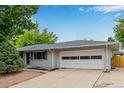 Well-maintained single-story home, painted gray, with a large two car garage and mature landscaping at 8231 E Lehigh Dr, Denver, CO 80237